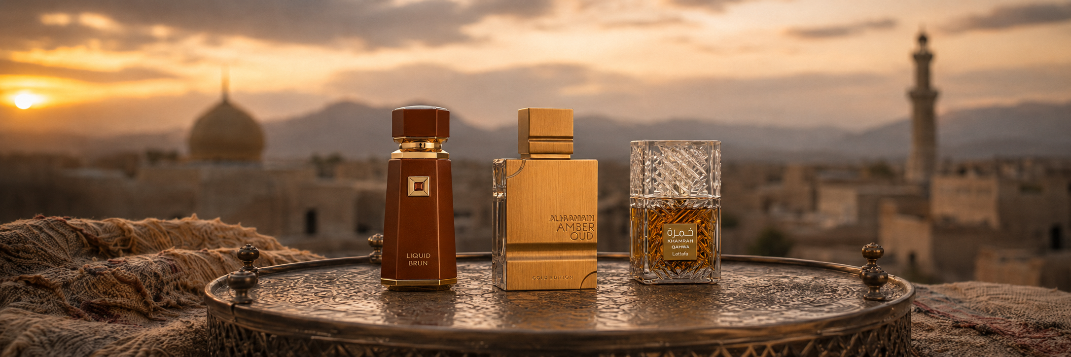 Three perfume bottles on a table with a scenic background of mountains and buildings.